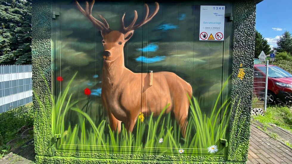 Ein Hirsch im Gras an der Wand.