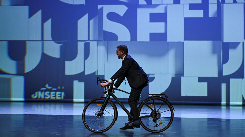 Sachsens Ministerpräsident Michael Kretschmer (CDU) fährt mit dem Fahrrad auf die Bühne vor dem offiziellen Festakt zur Eröffnung