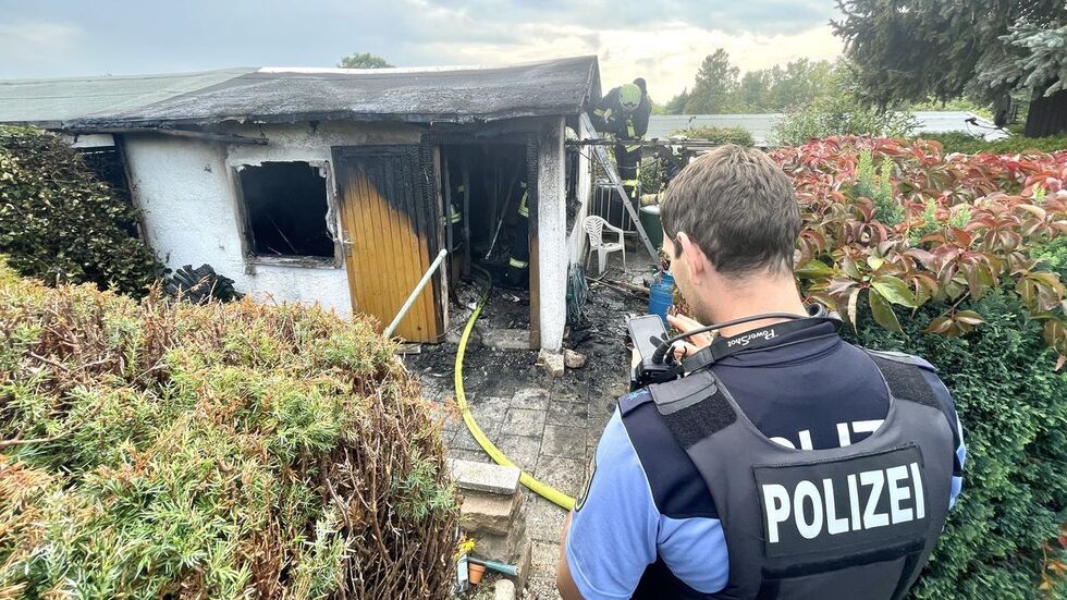 Ermittler vor ausgebrannter Laube