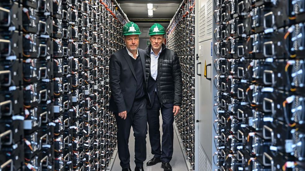 Bundeswirtschaftsminister Robert Habeck (l.) und Leag-Vorstand Thorsten Kramer stehen bei einem Rundgang über das Gelände vom Braunkohlekraftwerk Schwarze Pumpe in einem Batteriespeicher.     