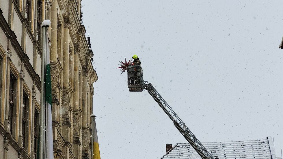 Ein Feuerwehrmann bringt einen Herrnhuter Stern am Görlitzer Rathaus an.