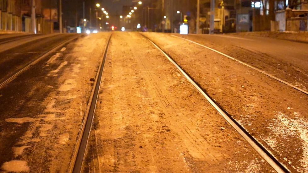 Gleise einer Straßenbahn liegen auf der vereisten Straße.