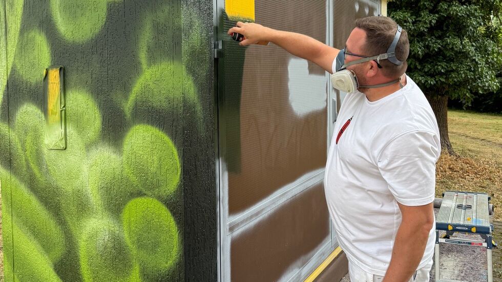 Ein Graffiti-Künstler beim Besprühen eines Mitnetz-Stromhäuschens an der Krakauer Straße in Markranstädt.
