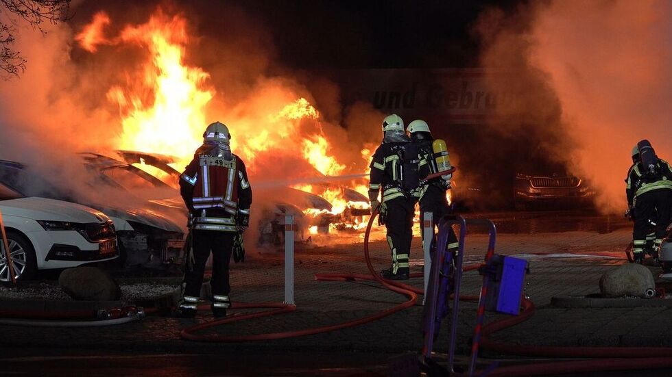 Einsatzkräfte löschen die brennenden Fahrzeuge vor dem Autohaus