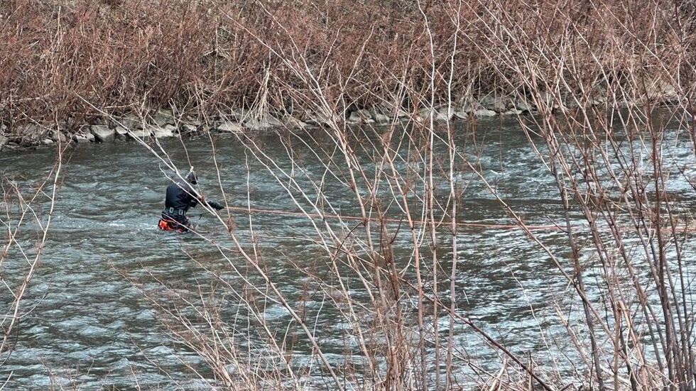 Ein Polizeitaucher hält sich wegen der starken Strömung an einem Seil fest.
