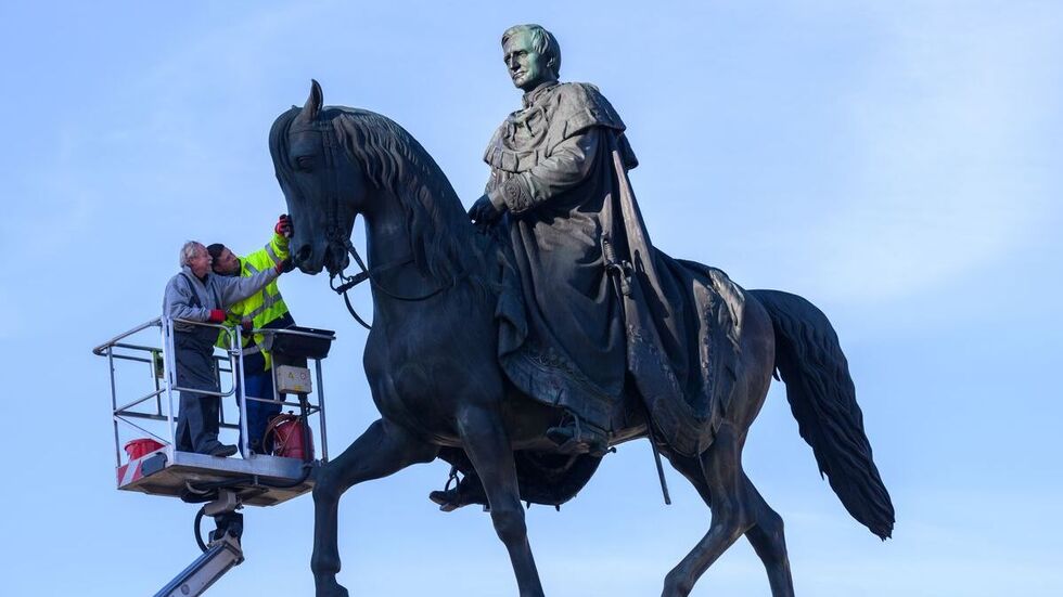 Denkmalpfleger Andreas Kunze (l) und Christopher Rath von der Restaurationsfirma Fuchs & Girke untersuchen auf dem Theaterplatz das Reiterstandbild König Johann.