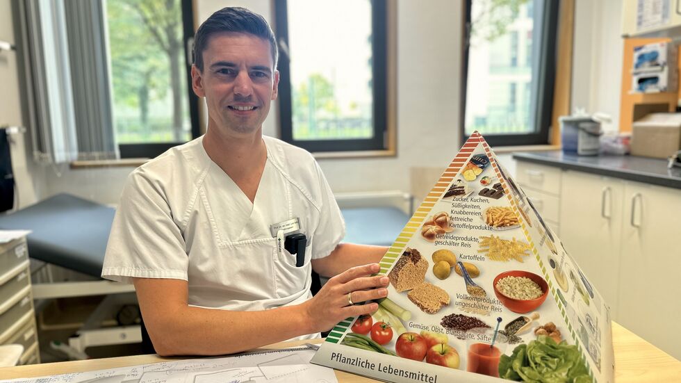 Professor Dr. Lars Selig, Experte für Ernährungsmedizin am Uniklinikum Leipzig, hält eine Ernährungspyramide in der Hand.