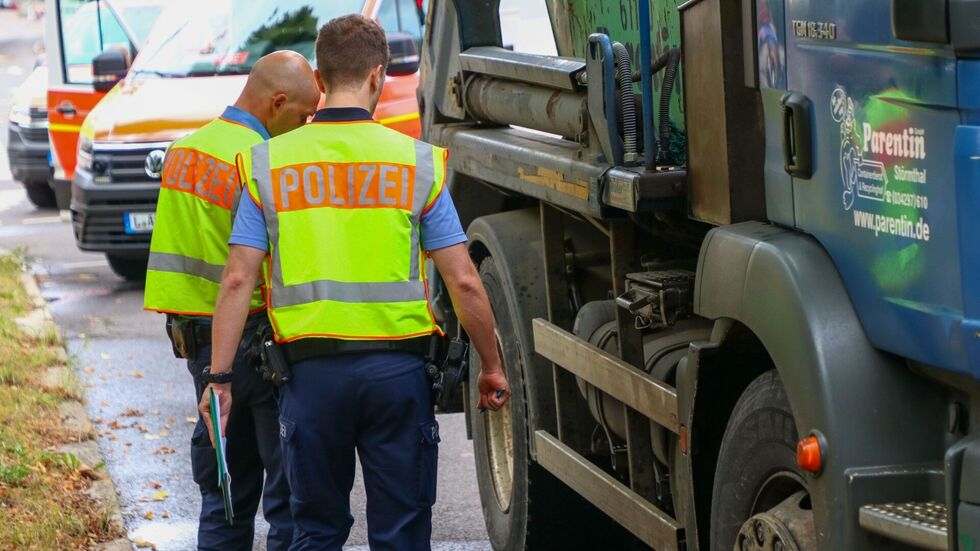 Polizisten untersuchen den Unfall-LKW.