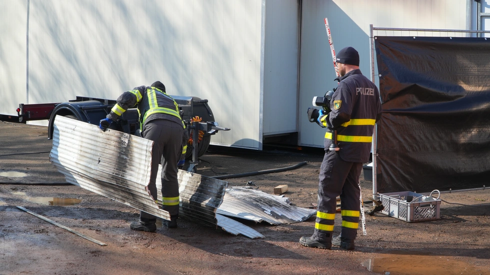 Polizisten untersuchen den Brandort. Polizisten untersuchen den Brandort.