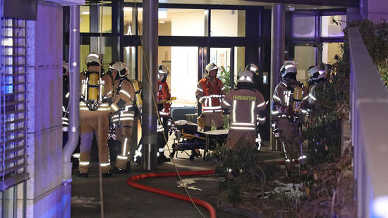 Die Einsatzkräfte rollen eine Trage aus der Pflegeeinrichtung.