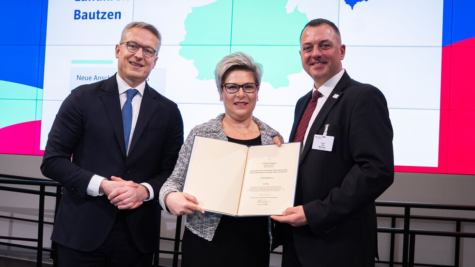 Landrat Udo Witschas und Beigeordnete Romy Reinisch nehmen die Bescheide von Digitalminister entgegen.