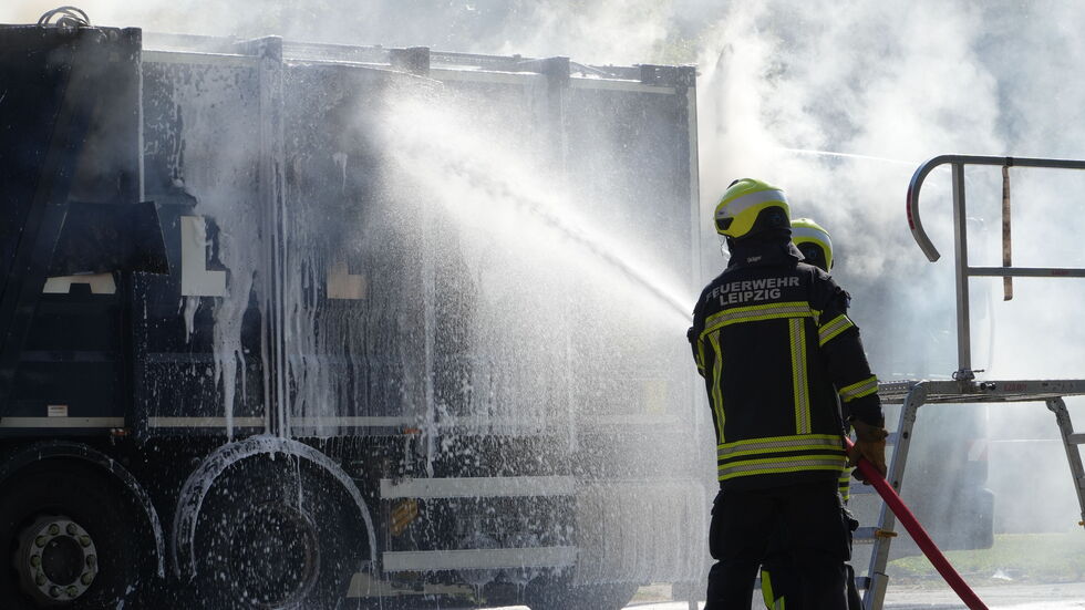 Feuerwehrleute beim Löschen des brennenden Müllfahrzeuges.