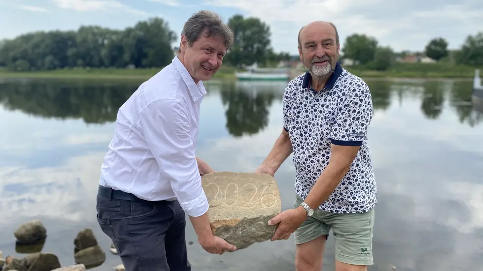v. l.: Olaf Lier, Leiter des Fachbereichs Ordnungswesen, und Steffen Spindler, ehemaliger Lehrer, heben den Hungerstein in die Elbe