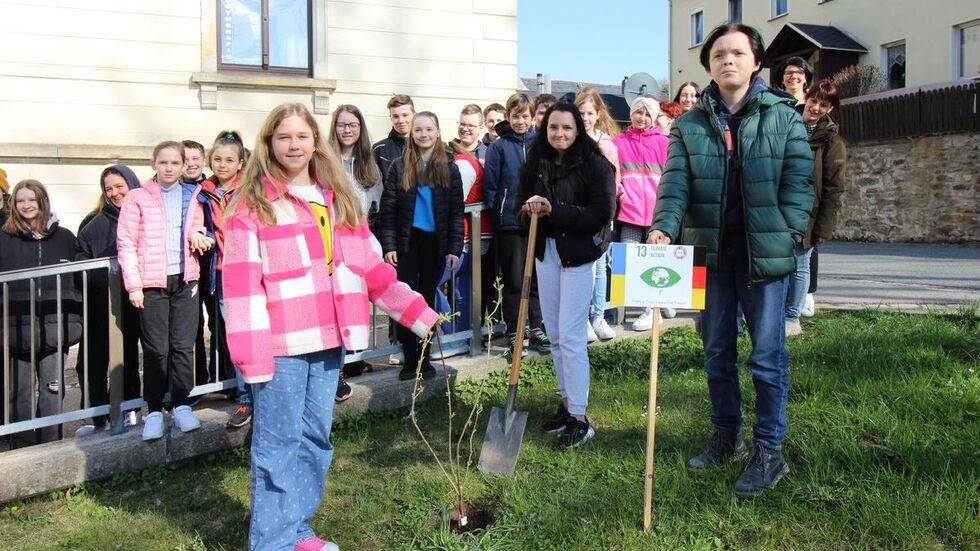 Ukrainische und deutsche Schüler pflanzen gemeinsam einen Baum.