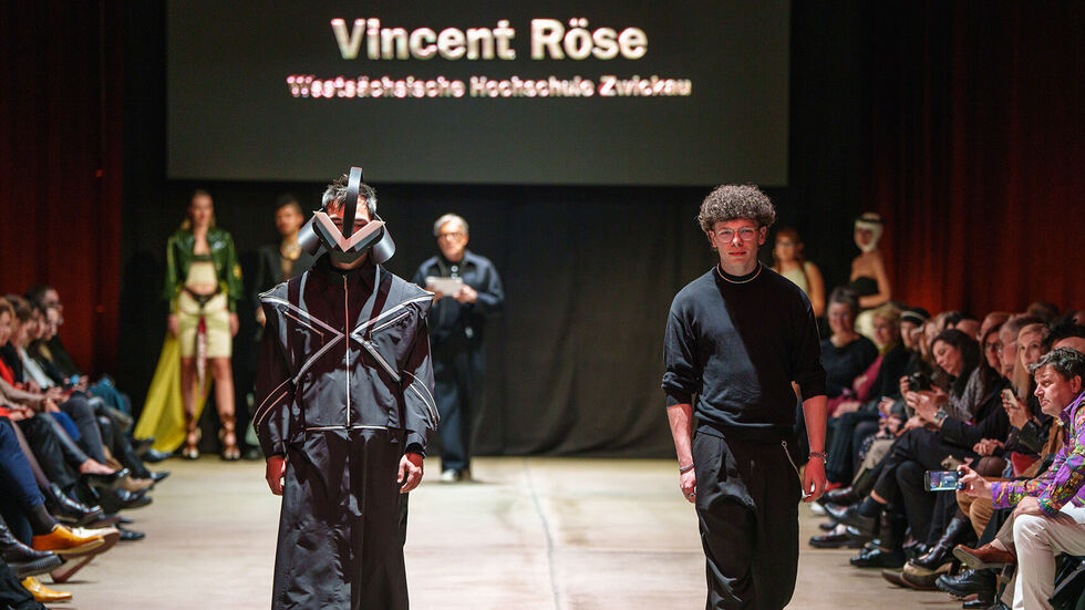 Ein Model (li.) trägt das preisgekrönte Designerstück auf dem Laufsteg - rechts daneben Vincent Röse.
