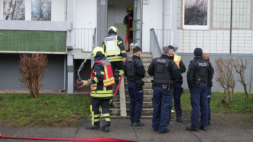 Einsatzkräfte vor dem betroffenen Hauseingang des 11-geschossigen Plattenbaus.