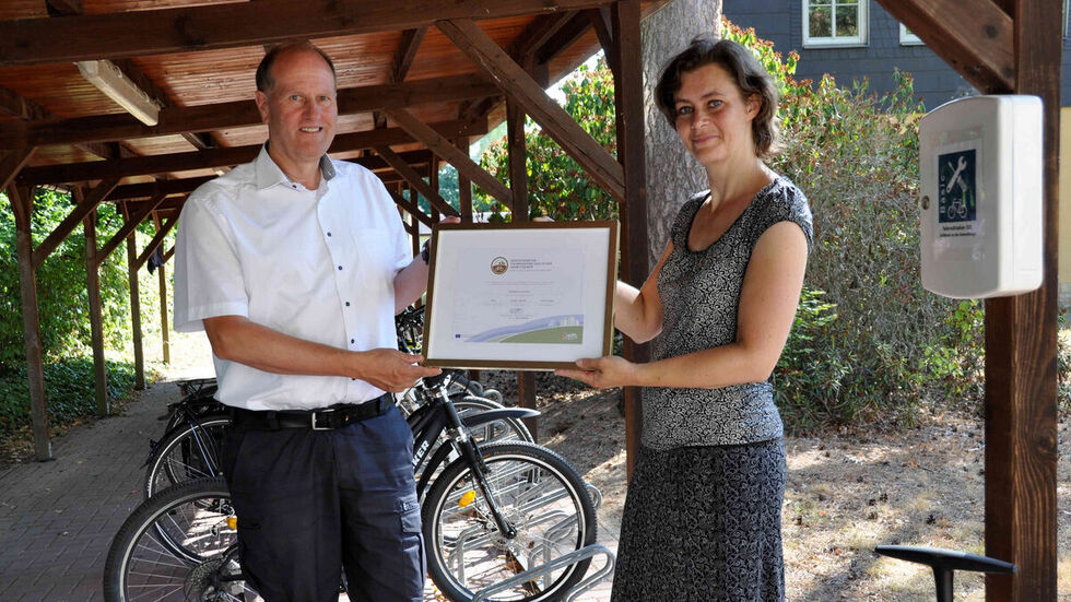 Die stellvertretende Vorsitzende des ADFC Sachsen e.V., Rosalie Kreuijer (rechts), übergibt dem Geschäftsführer von Sachsenforst, Utz Hempfling, das Zertifikat als fahrradfreundlicher Arbeitgeber für den Standort Graupa in Bronze.